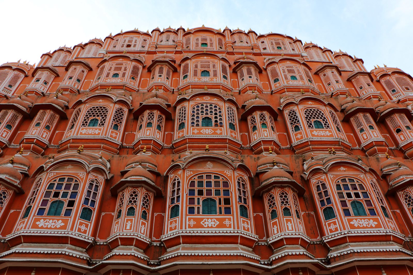 Pink sandstone honeycomb facade of Hawa Mahal with rows of latticed jharokha windows in Jaipur old city
