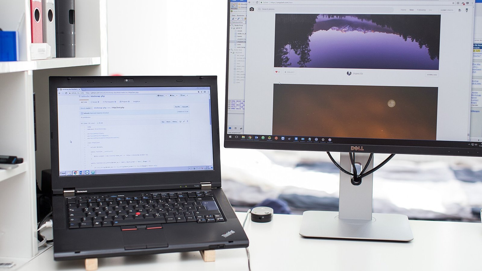 Laptop raised on small wooden blocks beside an external monitor on a white desk, showing a laptop stand and monitor height setup